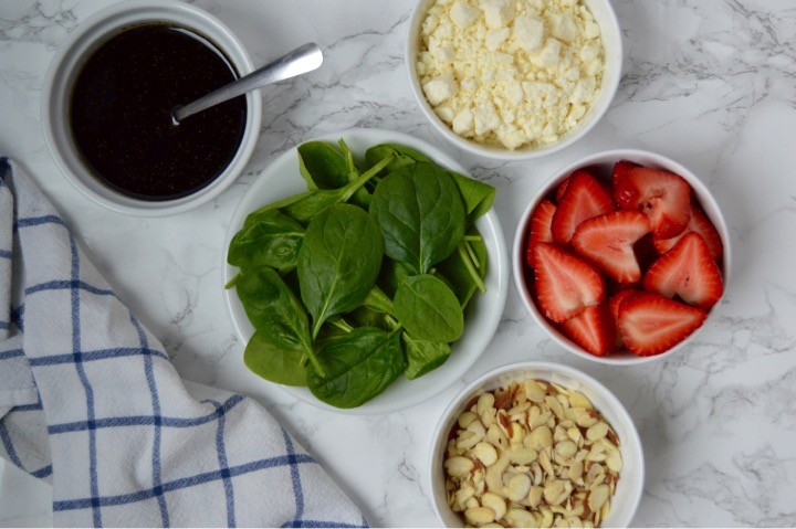 Strawberry Spinach Salad with sliced almonds, feta cheese, and a Honey Balsamic Vinaigrette Dressing | Easy Easter dinner menu for the family. Fresh, springtime dinner with vegetable lasagna main course, strawberry spinach salad, rolls, + milkshake dessert.