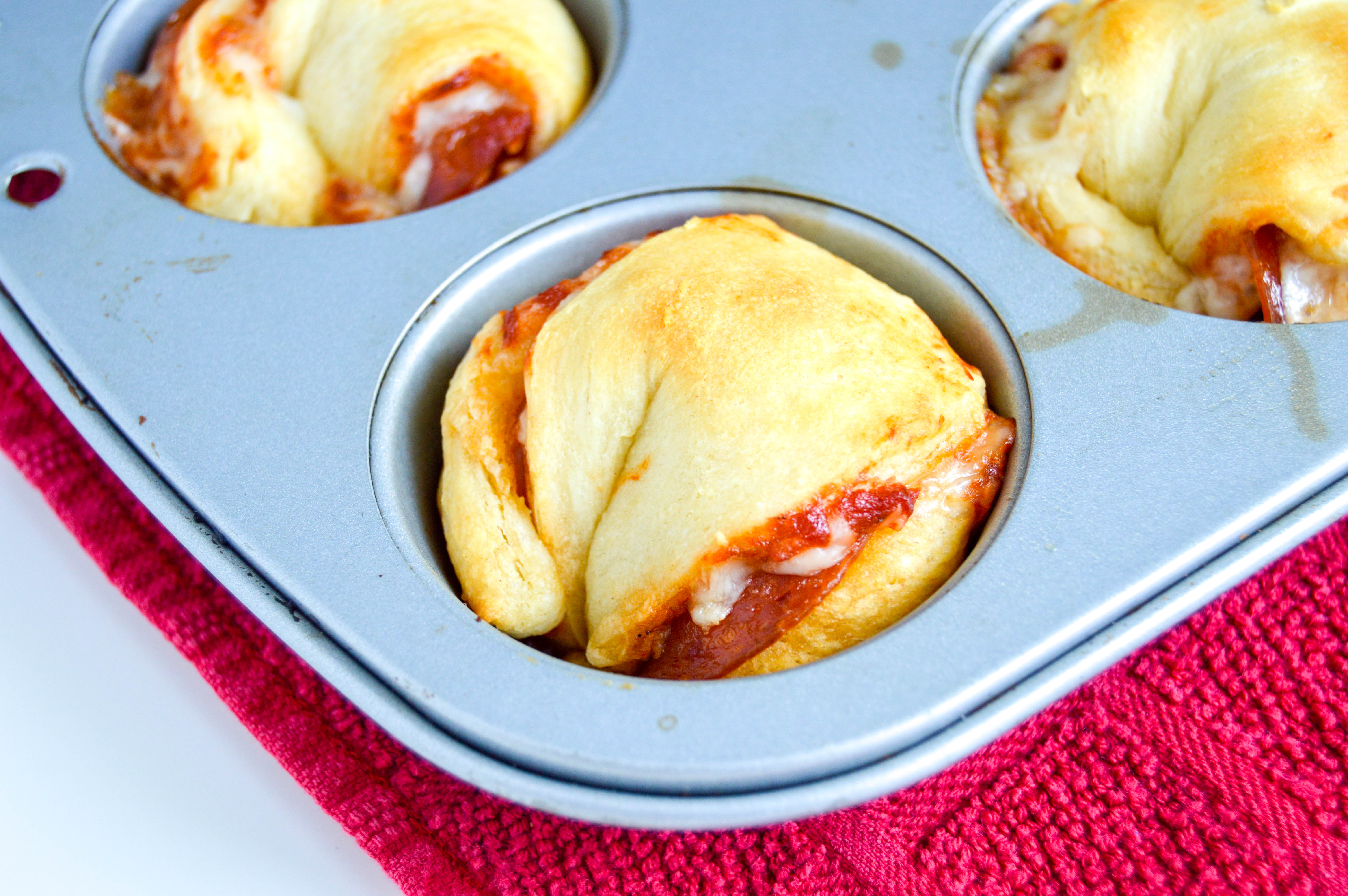 Pizza muffins are a super easy and cheap way to make pizza at home. Pre-made Crescent Dinner Roll dough and a few simple ingredients popped in a muffin tin and baked in the oven. Definitely a dinner the kids will love or the perfect savory party appetizer.