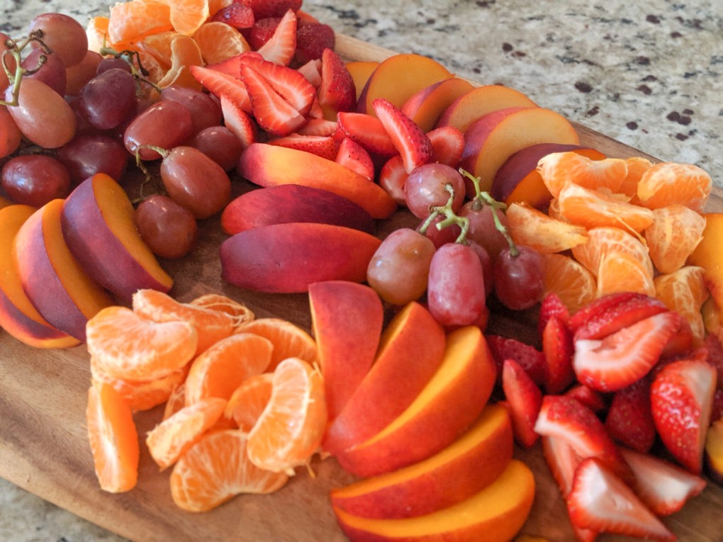 Beautiful fruit tray with peaches, strawberries, clementines, and red grapes.